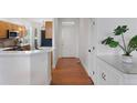 Bright hallway features hardwood floors and flows seamlessly towards a modern kitchen with white counters and wood cabinets at 86 Woodland Cir, Highlands Ranch, CO 80126