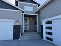 Front entrance with gray siding, stone accents, and a white door at 42978 Colonial Trl, Elizabeth, CO 80107