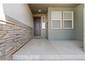 Inviting covered front porch with stone accents and an elegant entryway at 19409 W 88Th Dr, Arvada, CO 80007