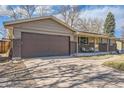 Ranch-style home with a spacious driveway, brick accents, and attached garage at 1255 S Hoyt St, Lakewood, CO 80232