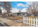 Charming single-story home featuring a fenced yard, mature trees, and a cozy front porch at 117 6Th St, Frederick, CO 80530