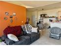 Cozy living room with a large couch, orange wall and view into the dining area at 14353 E 1St Dr # 302, Aurora, CO 80011