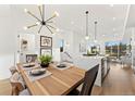 Bright and airy dining room with a modern chandelier, wood table, and open access to the living area at 2148 Applewood Dr, Lakewood, CO 80215