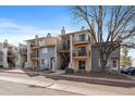 Exterior view of condos with balconies and staircases, showing the building's facade and nearby street under a blue sky at 6011 Yarrow St # C, Arvada, CO 80004