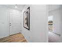 Neutral hallway with wood-look floors, a white door, and a calming abstract painting at 13543 E 103Rd Ave, Commerce City, CO 80022