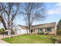 Landscaped front lawn of inviting home, complete with mature trees, brick facade, and manicured lawn at 6997 S Poplar Way, Centennial, CO 80112