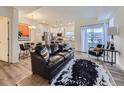 Open-concept living room featuring a modern black leather couch, area rug, and natural light at 12920 Jasmine St # F, Thornton, CO 80602