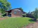 Well-kept brick home with a lush green lawn and mature trees at 2902 Depew St, Wheat Ridge, CO 80214