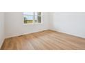 Bright bedroom with light wood-look flooring, white walls, and large window overlooking an open view at 45933 Wood Thrush Ave, Bennett, CO 80102