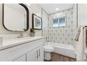 Updated bathroom featuring geometric tile accent wall, white vanity, and modern fixtures at 1227 Yost St, Aurora, CO 80011