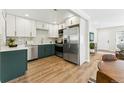 Modern kitchen features white and green cabinets, stainless steel appliances, and hardwood floors at 1227 Yost St, Aurora, CO 80011