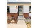 Front entry with brick and white siding, glass door, and landscaping at 4612 S Coors Ct, Morrison, CO 80465