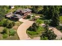 An aerial view of a well-maintained home with lush landscaping, a circular driveway, and mature trees providing privacy at 8836 Marathon Rd, Longmont, CO 80503