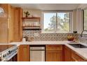 This kitchen features wooden cabinets, stainless steel appliances, a large window and a decorative tile backsplash at 11358 W 85Th Pl # E, Arvada, CO 80005