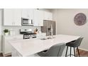 Bright kitchen showcasing white cabinetry, a stainless steel microwave, and a large island at 6393 N Malaya St, Aurora, CO 80019