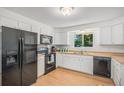 A bright kitchen featuring white cabinetry, modern black appliances, and a stainless steel sink under a window at 1641 Biscay Cir, Aurora, CO 80011