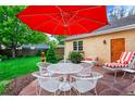 Outdoor patio featuring a table, chairs, a red umbrella, and manicured shrubs at 2411 S Milwaukee St, Denver, CO 80210