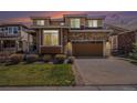 Charming two-story home boasts a stone and siding exterior, paired with an attached two-car garage and lush lawn at 7004 S Addison Ct, Aurora, CO 80016