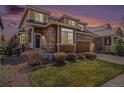 Beautiful two-story home featuring a stone facade, manicured lawn, and inviting front entrance with a modern wood door at 7004 S Addison Ct, Aurora, CO 80016