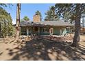 Charming single-story house with stone chimney, covered porch, and surrounding trees at 28539 Douglas Park Rd, Evergreen, CO 80439