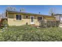 Ranch style home with charming yellow paint, nice landscaping, and solar panels on the roof at 15645 E Floyd Ave, Aurora, CO 80013