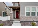 Two-story home featuring a covered front porch with brick accents and a red front door at 5152 Bittercress Rd, Brighton, CO 80640
