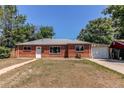 Red brick home featuring a well-kept lawn, and an attached garage with a driveway at 9150 Lilly Ct, Thornton, CO 80229