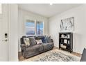 Cozy living room features a comfy grey couch, neutral rug, bookshelf, and natural light, creating a welcoming atmosphere at 15833 Little Bluestem Rd, Monument, CO 80132