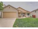 Charming single-Gathering home with a manicured lawn, covered porch, and brick accents on the garage and entrance at 5394 S Valdai Way, Aurora, CO 80015