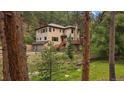 Exterior of a home featuring a spacious deck with trees and serene landscaping at 27756 Troublesome Gulch Rd, Evergreen, CO 80439