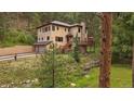 Exterior of a two-story home featuring a spacious deck and serene landscaping at 27756 Troublesome Gulch Rd, Evergreen, CO 80439