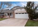 Charming home featuring a two-car garage, stone accents, and a welcoming covered porch at 9450 Troon Village Dr, Lone Tree, CO 80124