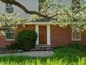 Inviting brick home featuring a wooden front door with sidelights and mature landscaping at 11824 E Basswood Ln, Franktown, CO 80116