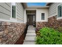 Inviting front entrance with stone accents, a covered porch, and a well-maintained landscape at 23130 E Del Norte Cir, Aurora, CO 80016