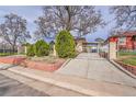 View of the front of this home, showcasing well-maintained landscaping and secure gated driveway at 4940 Adams St, Denver, CO 80216