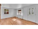 Bright living room featuring hardwood floors, fresh paint, and natural light through two large windows at 4940 Adams St, Denver, CO 80216