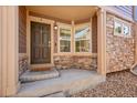 Inviting front entryway with brown door, stone accents, and cozy welcome mat at 5660 S Algonquian Way # A, Aurora, CO 80016