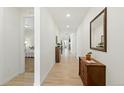 Long hallway with light wood floors, white walls, leading to the bedroom and kitchen at 8844 S Sicily Ct, Aurora, CO 80016