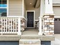 Inviting covered front porch with stone detailing on the columns and railing at 571 Homestead Ave, Brighton, CO 80601