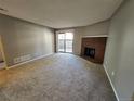 Comfortable living room with a brick fireplace, carpet, and sliding glass doors to the patio at 14499 E 1St Dr # A05, Aurora, CO 80011