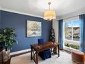 Elegant office with a wooden desk, blue accent wall, bright window, and stylish decor at 12431 Red Fox Way, Broomfield, CO 80021