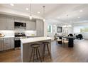 Open concept kitchen with stainless appliances, kitchen island, pendant lighting, and adjacent dining and living area at 8408 W 52Nd Ave, Arvada, CO 80002