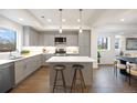 Modern kitchen with stainless steel appliances, quartz counters, center island with seating, and open to dining area at 8408 W 52Nd Ave, Arvada, CO 80002