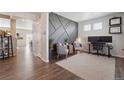 Home office features wood floors, gray accent wall, and view into adjacent living space at 1123 Sunrise Dr, Brighton, CO 80603