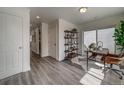 Hallway with hardwood floors leading to an office with modern shelving and sliding glass door at 10379 Vaughn Way, Commerce City, CO 80022