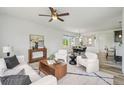 Cozy living room with a modern ceiling fan, white walls, and a view into the dining area at 198 Starlight Cir, Erie, CO 80516