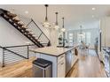 Bright, open kitchen with a large island, pendant lights, adjacent to a staircase with black metal railings at 4170 Vrain St, Denver, CO 80212