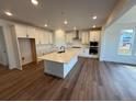 Bright and airy kitchen features white cabinets, stainless appliances, large island, and wood floors at 1131 Joseph Pl, Erie, CO 80026