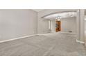 Spacious living room with neutral walls, plush gray carpet, arched entryways, and an elegant tray ceiling with chandelier at 15378 E 99Th Way, Commerce City, CO 80022