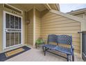 Charming front porch with a cozy bench, 'welcome' doormat, and decorative floral wreath on the front door at 10056 W Unser Dr # 204, Littleton, CO 80127